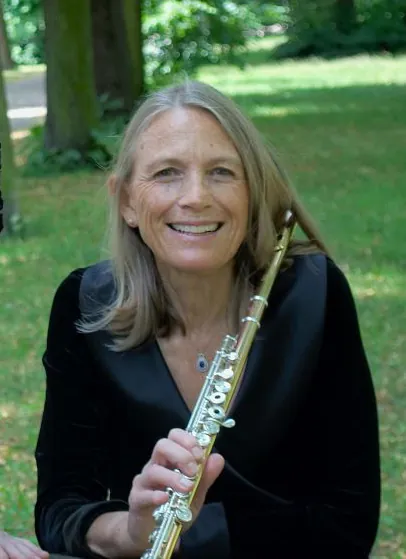 Barbara Hill smiling, holding her flute in a park