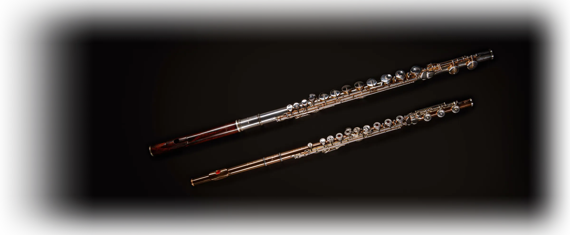 Two flutes lying side by side on a dark background